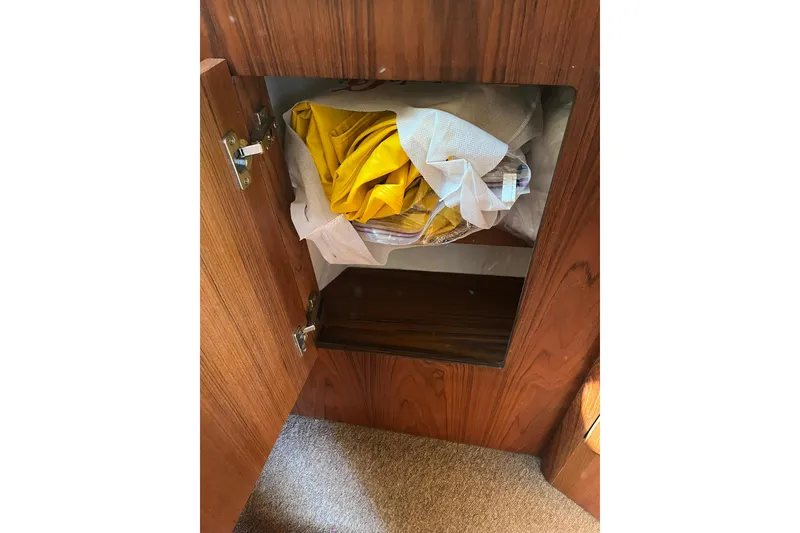 Slide: The Image of Open wooden cabinet on 1996 Tiara Yachts 3500 Express, storing yellow and white fabric. - 77