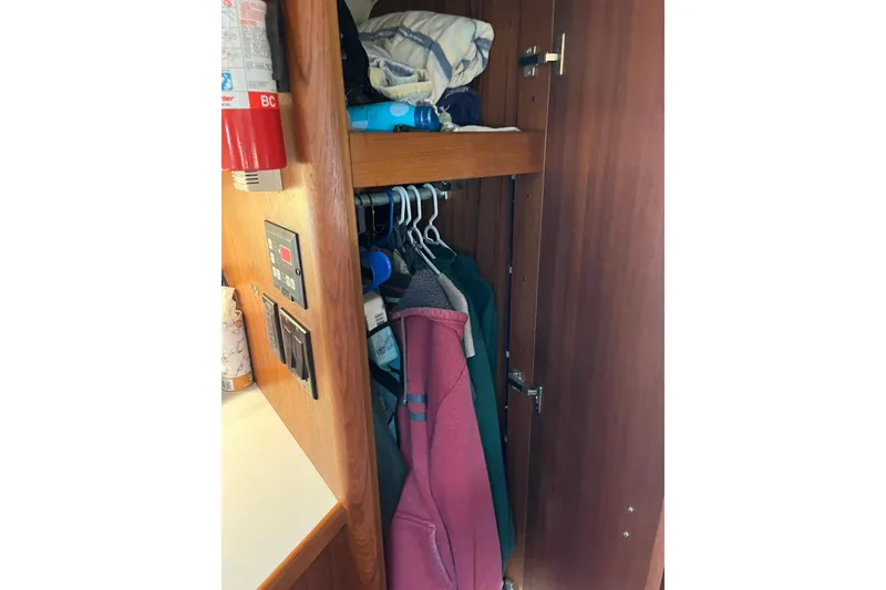Slide: The Image of Cabinet interior on 1996 Tiara Yachts 3500 Express, with clothes and fire extinguisher. - 78