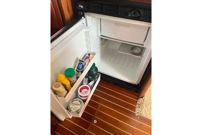 Slide: The Image of Open refrigerator on 1996 Tiara Yachts 3500 Express, stocked with condiments and dairy products. - 83
