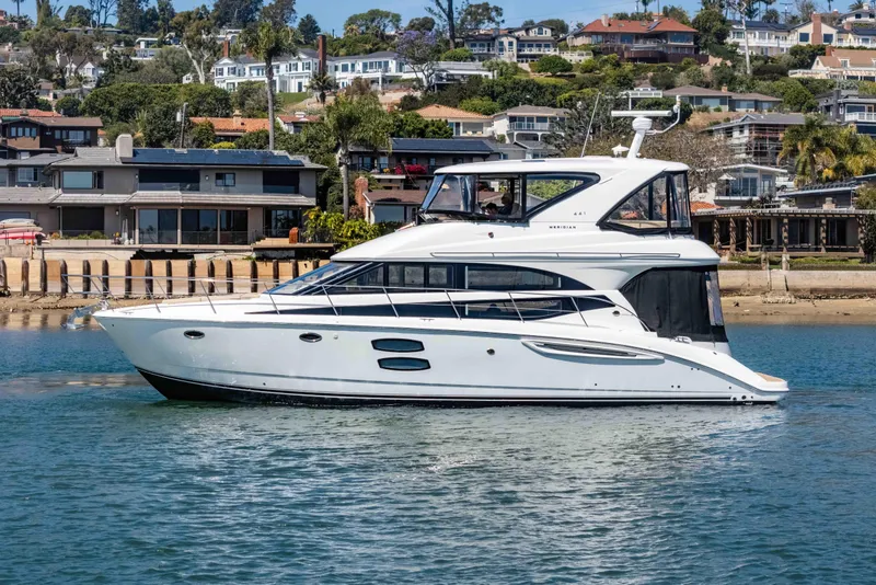 Slide: The Image of 2016 Meridian 441 Sedan yacht cruising near coastal homes. - 5
