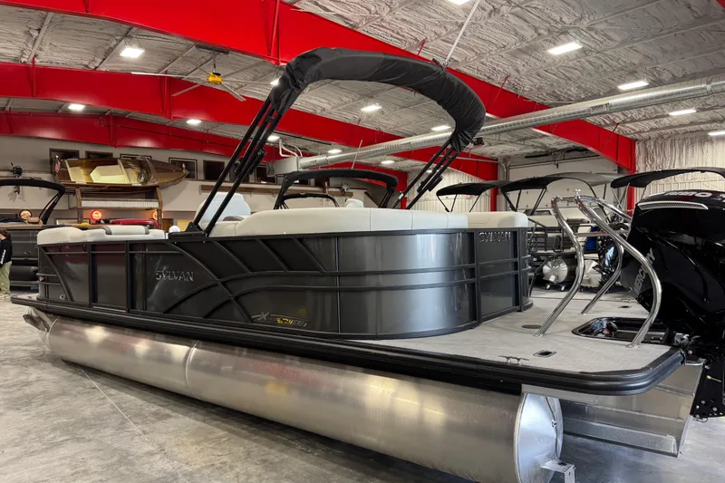 Slide: The Image of 2026 Sylvan Mirage X X5 pontoon boat in showroom with red ceiling accents. - 5