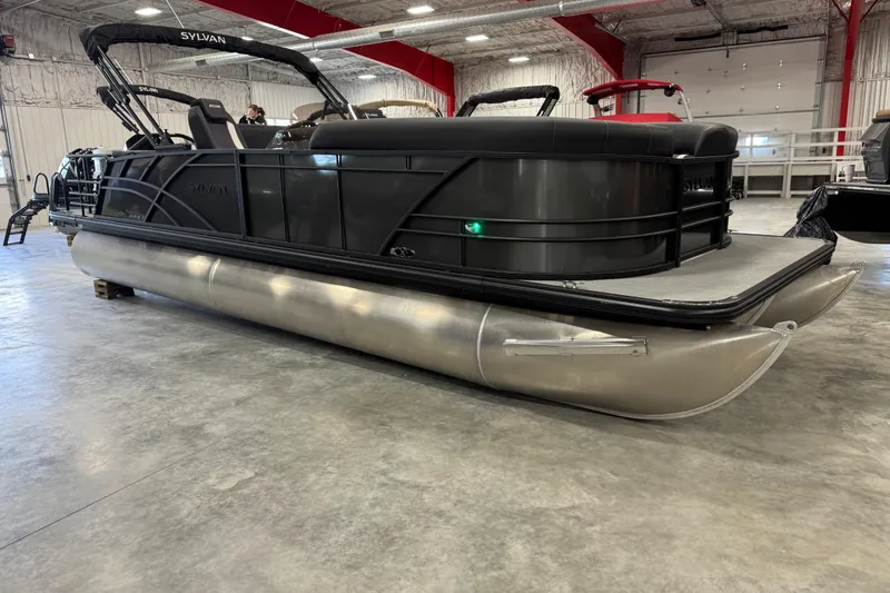 Slide: The Image of 2026 Sylvan X5 pontoon boat in a showroom, featuring sleek black design. - 2
