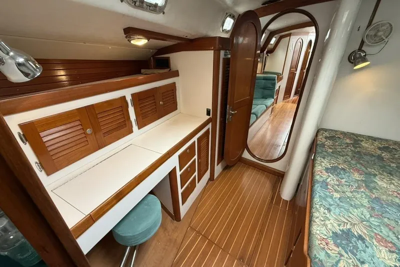 Slide: The Image of Interior of a 1996 J Boats J/160 yacht, featuring wood cabinetry and a cozy seating area. - 16