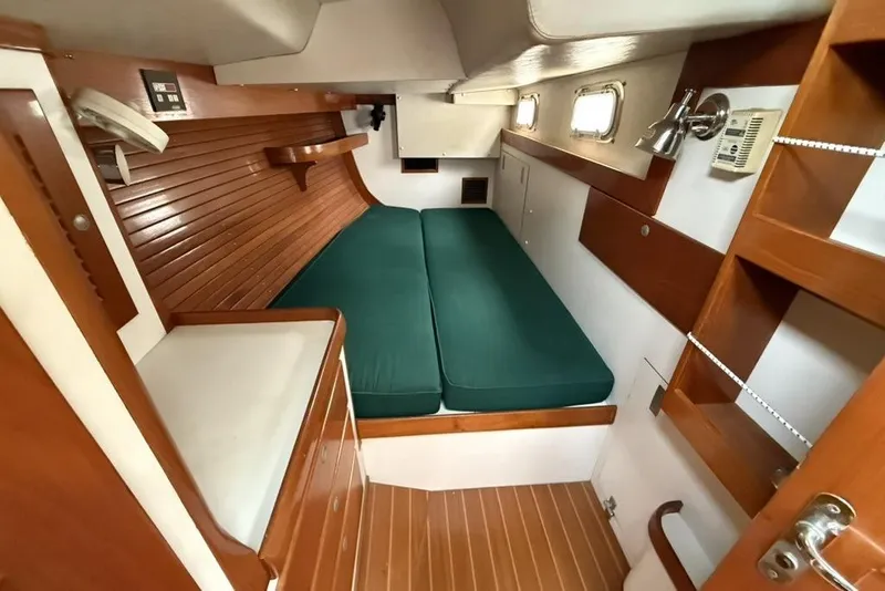 Slide: The Image of Interior cabin of a 1996 J Boats J/160 sailboat with wooden finish and green cushions. - 21