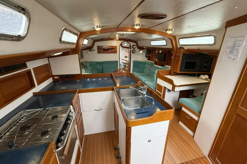 Slide: The Image of Interior of 1996 J Boats J/160 yacht featuring kitchen, seating, and wooden accents. - 4