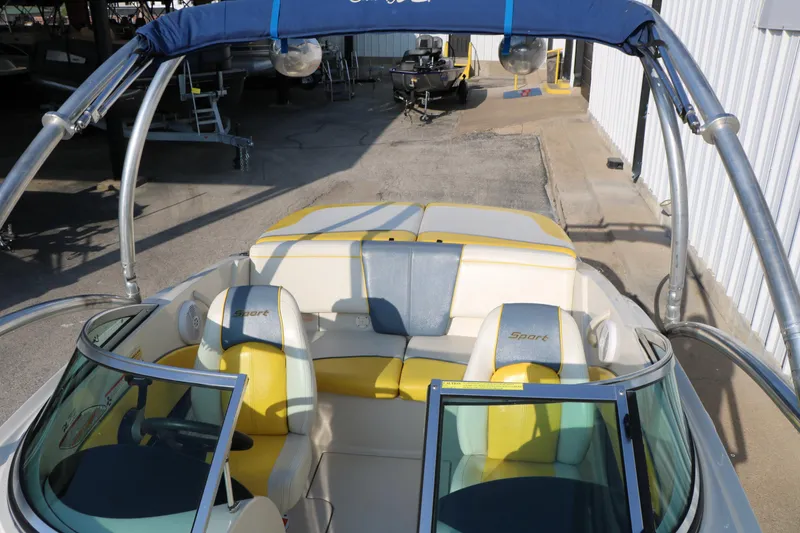 Slide: The Image of 2006 Sea Ray 185 Sport boat interior with yellow and white seating, parked in a marina. - 30