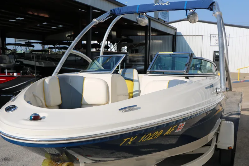 Slide: The Image of 2006 Sea Ray 185 Sport boat with blue and white exterior, parked in a marina. - 6