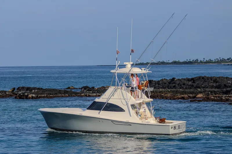 The Image of 2017 Viking 37 Billfish yacht cruising near rocky shoreline under clear blue sky. - 0