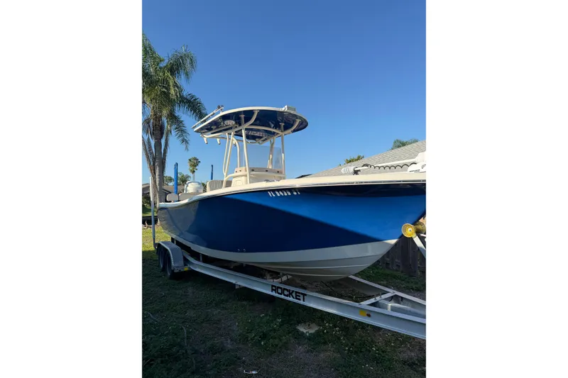 The Image of 2019 Sea Chaser 24 HFC boat on trailer, blue hull, palm trees in background. - 1
