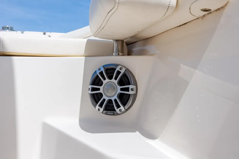 Slide: The Image of 2024 Grady-White Fisherman 236 boat speaker detail with white seating and blue sky background. - 50