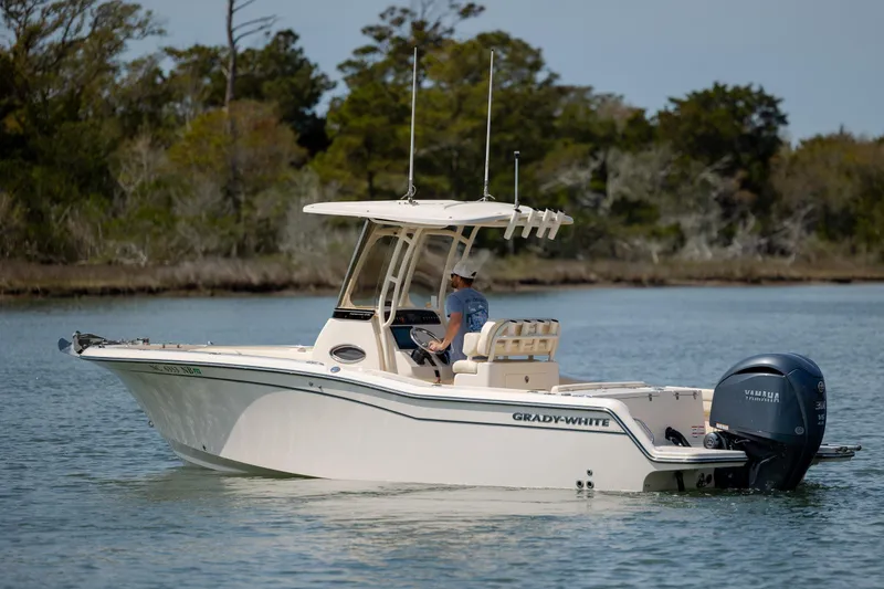 Slide: The Image of 2024 Grady-White Fisherman 236 boat cruising on a calm lake with trees in the background. - 6