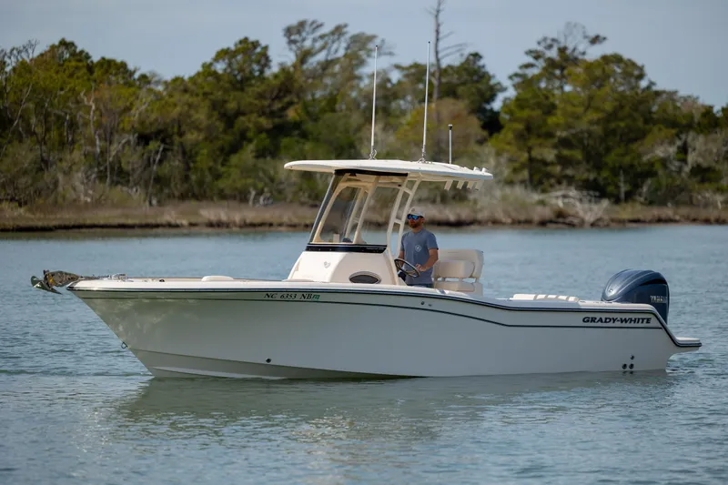 Slide: The Image of 2024 Grady-White Fisherman 236 boat on calm water, with trees in the background. - 8