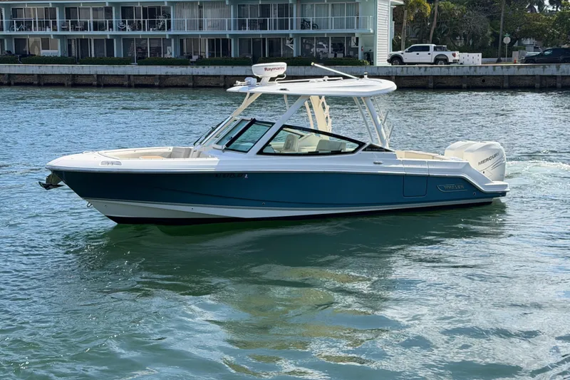 The Image of 2021 Boston Whaler 280 Vantage boat cruising on water near waterfront buildings. - 0