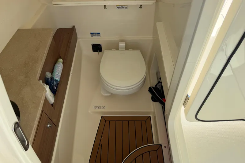 Slide: The Image of 2021 Boston Whaler 280 Vantage boat bathroom with toilet and storage shelves. - 12
