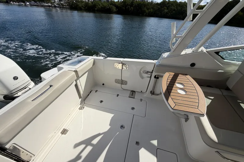 Slide: The Image of 2021 Boston Whaler 280 Vantage boat interior with seating and table on calm water. - 16