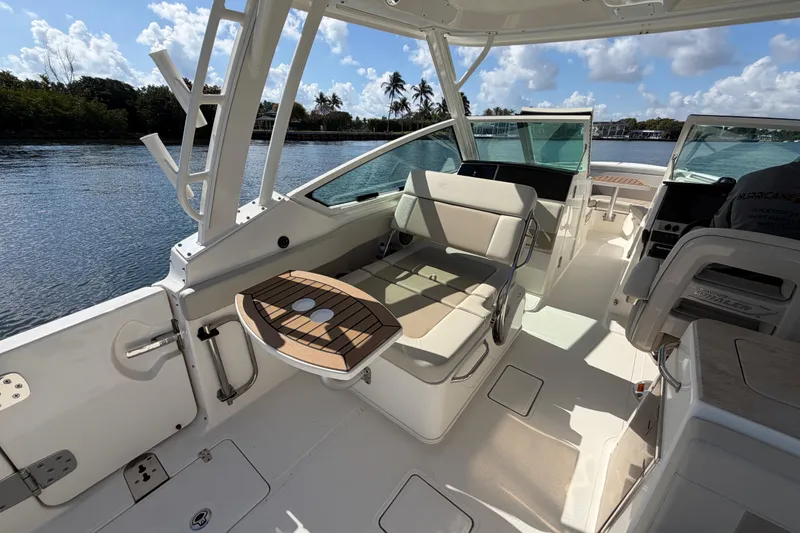 Slide: The Image of 2021 Boston Whaler 280 Vantage boat interior with seating and table, docked by a scenic waterway. - 19