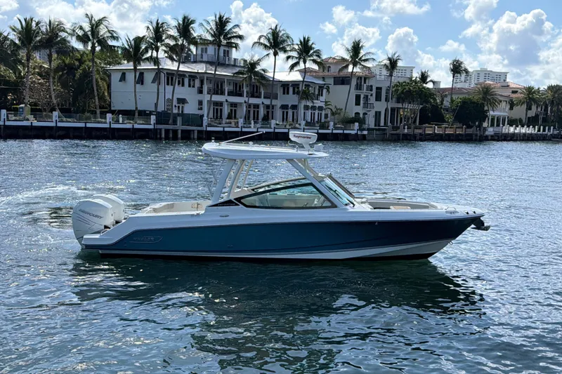 Slide: The Image of 2021 Boston Whaler 280 Vantage boat cruising on a sunny waterfront with palm trees. - 2