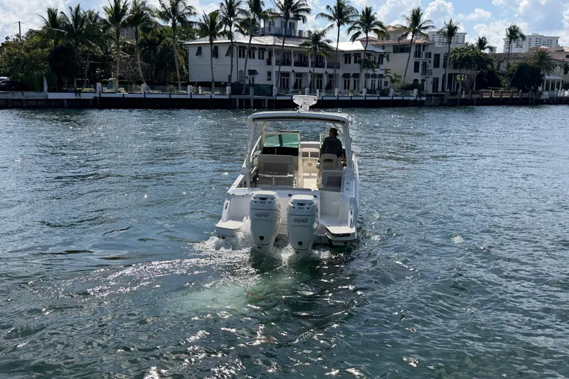 Slide: The Image of 2021 Boston Whaler 280 Vantage cruising on a sunny waterfront with palm trees. - 28