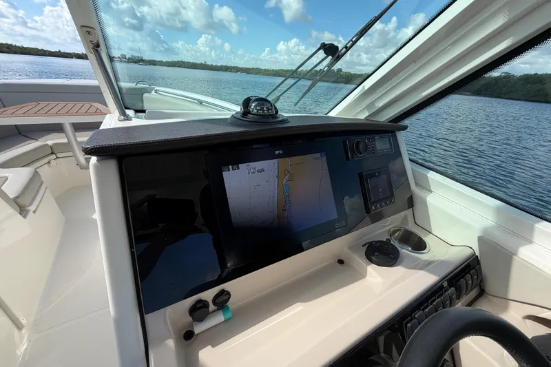 Slide: The Image of 2021 Boston Whaler 280 Vantage helm with navigation display, steering wheel, and scenic water view. - 3