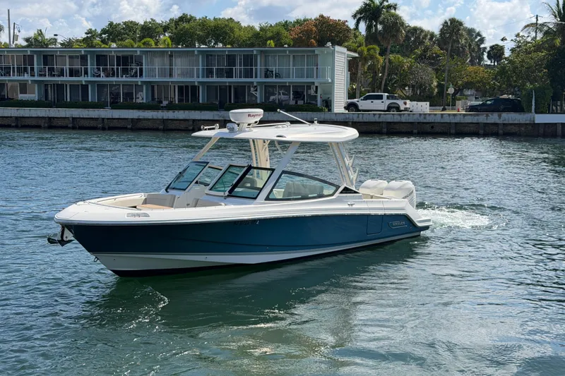 Slide: The Image of 2021 Boston Whaler 280 Vantage boat cruising on a sunny waterfront near modern buildings. - 35