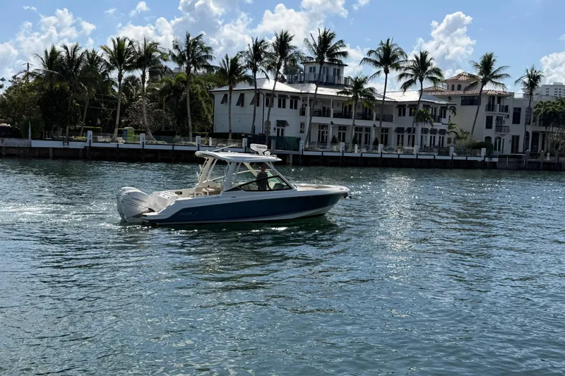 Slide: The Image of 2021 Boston Whaler 280 Vantage cruising on a sunny waterfront with palm trees. - 41