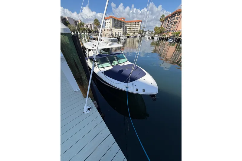 Slide: The Image of 2021 Boston Whaler 280 Vantage docked in a marina, surrounded by buildings and calm water. - 44