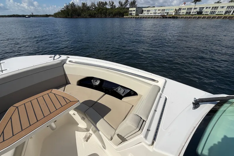 Slide: The Image of 2021 Boston Whaler 280 Vantage boat interior with seating and table on calm water. - 5