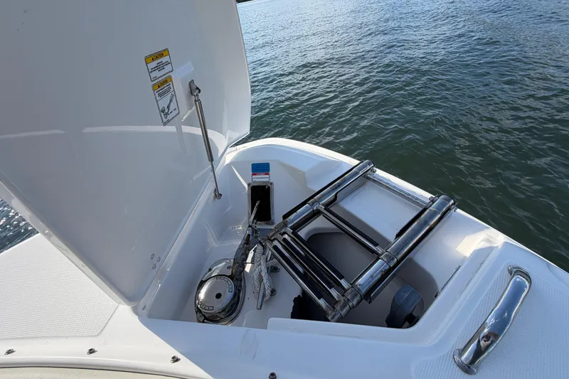 Slide: The Image of 2021 Boston Whaler 280 Vantage boat with open anchor locker and ladder, on water. - 7
