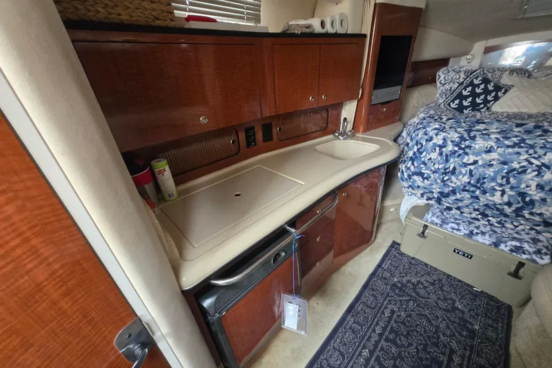 Slide: The Image of 2003 Sea Ray Sundancer 320 cabin interior with kitchenette, sink, and cozy bedding area. - 18