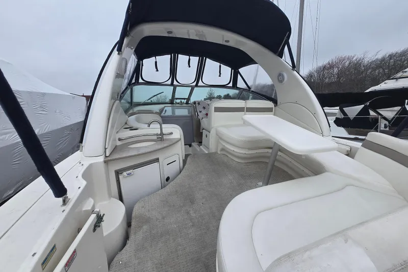 Slide: The Image of 2003 Sea Ray Sundancer 320 interior with seating, table, and helm under a canopy. - 24