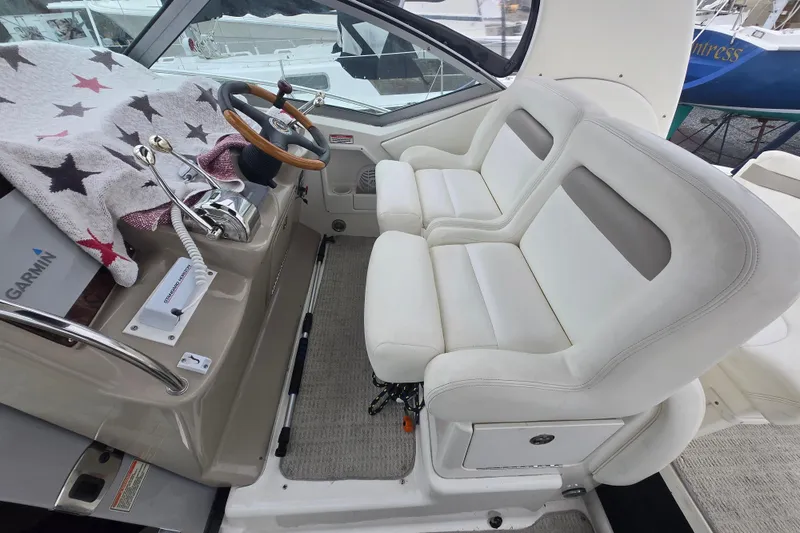 Slide: The Image of 2003 Sea Ray Sundancer 320 helm with dual white seats and wooden steering wheel. - 7
