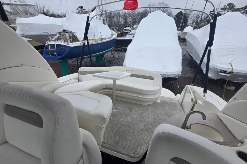 Slide: The Image of 2003 Sea Ray Sundancer 320 interior with seating and table, surrounded by covered boats. - 9