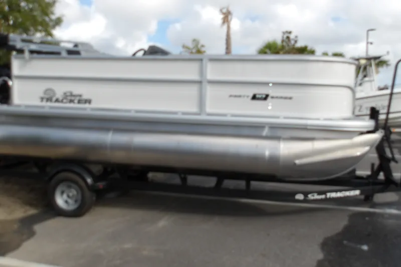 The Image of 2026 Sun Tracker Party Barge 18 DLX pontoon boat on trailer, parked outdoors. - 1