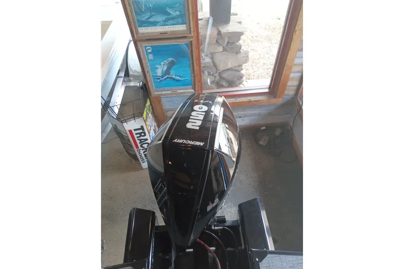 Slide: The Image of Outboard motor on a 2026 Regency 230 DL boat, indoors with marine posters. - 10