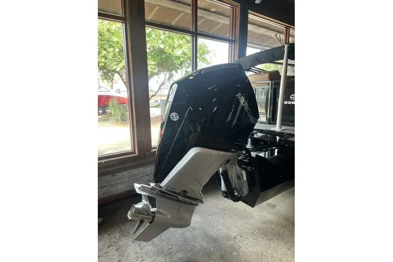 Slide: The Image of 2026 Regency 230 DL boat with Mercury outboard motor in showroom. - 5
