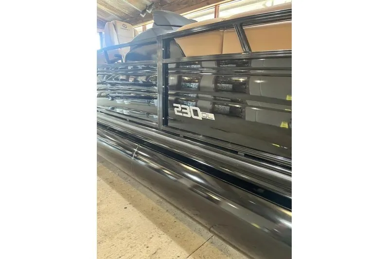 Slide: The Image of 2026 Regency 230 DL pontoon boat in a showroom, showcasing sleek black exterior design. - 2
