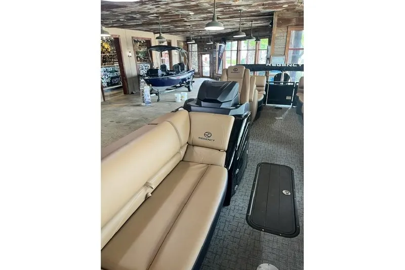 Slide: The Image of 2026 Regency 230 DL pontoon boat with beige seating in a showroom. - 6