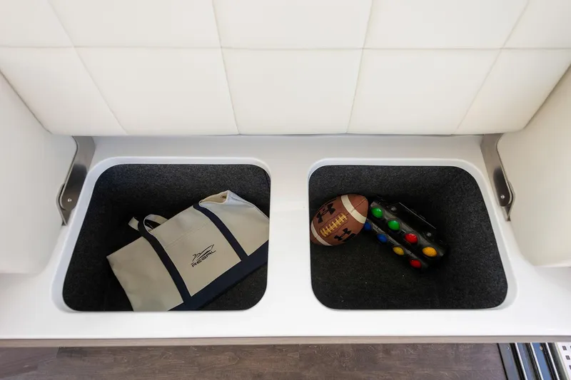 Slide: The Image of Manufacturer Provided Image: Storage compartments on a 2026 Regal 38 FXO boat with bag, football, and game controller. - 18