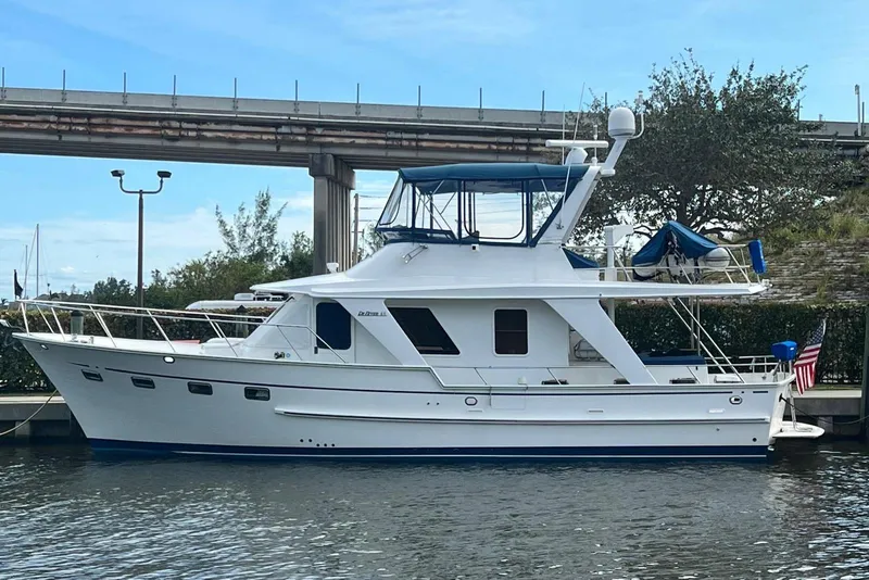 The Image of 2010 DeFever 48 Trawler docked, featuring a sleek white design and blue canopy. - 0