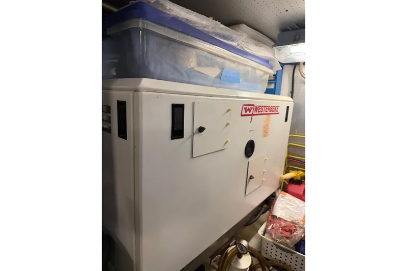 Slide: The Image of Westerbeke generator in a 2010 DeFever 48 Trawler engine room, with storage containers above. - 29