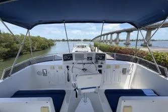 Slide: The Image of Cockpit view of 2010 DeFever 48 Trawler with blue canopy, navigating a scenic waterway. - 43