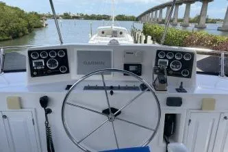 Slide: The Image of 2010 DeFever 48 Trawler helm with Garmin navigation, docked near a scenic bridge. - 45