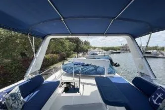 Slide: The Image of 2010 DeFever 48 Trawler with blue canopy, docked near lush greenery. - 48
