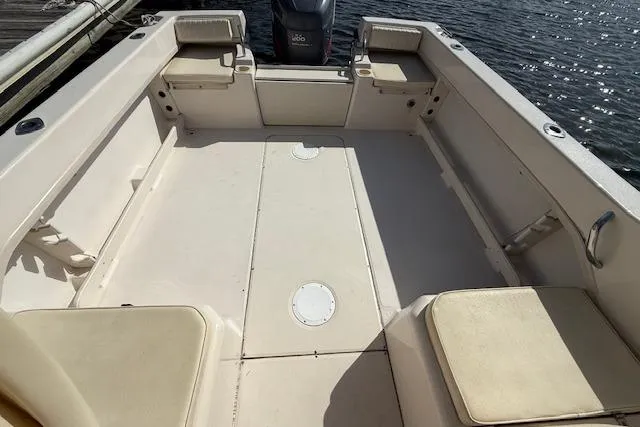 Slide: The Image of 2000 Grady-White Seafarer 22 boat interior with seating and motor, docked by water. - 10