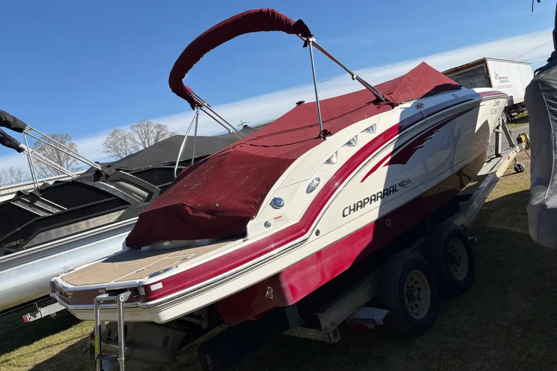 Slide: The Image of 2013 Chaparral 244 Sunesta boat with red cover on trailer, parked outdoors. - 2