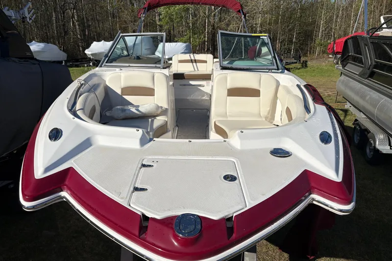 Slide: The Image of 2013 Chaparral 244 Sunesta boat with red and white exterior, parked outdoors. - 3