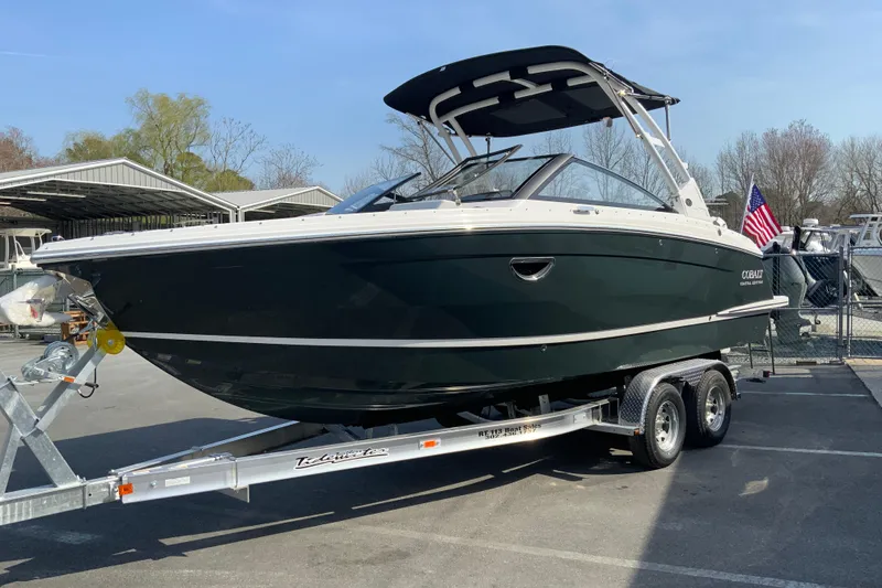 Slide: The Image of 2026 Cobalt R6 Outboard boat on trailer, parked outdoors with American flag. - 11