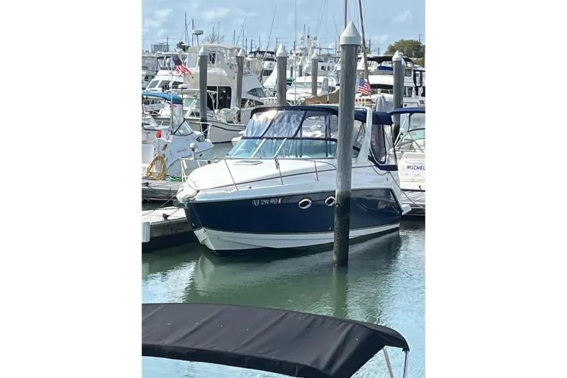 Slide: The Image of 2005 Rinker Fiesta Vee 270 boat docked in a marina, surrounded by other vessels. - 12