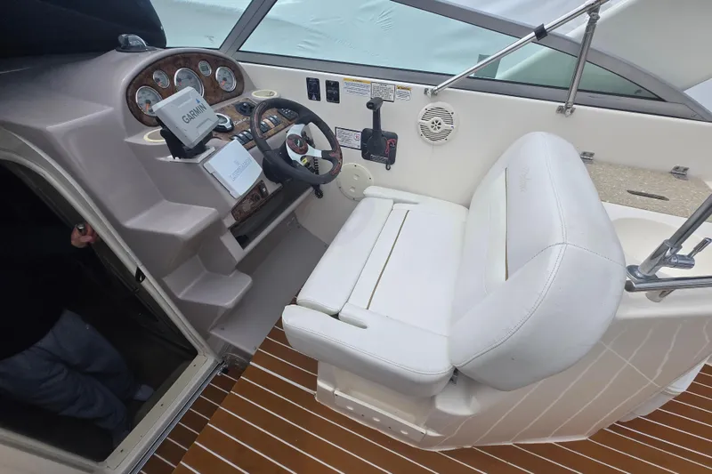 Slide: The Image of 2005 Rinker Fiesta Vee 270 boat cockpit with steering wheel and white seating. - 18