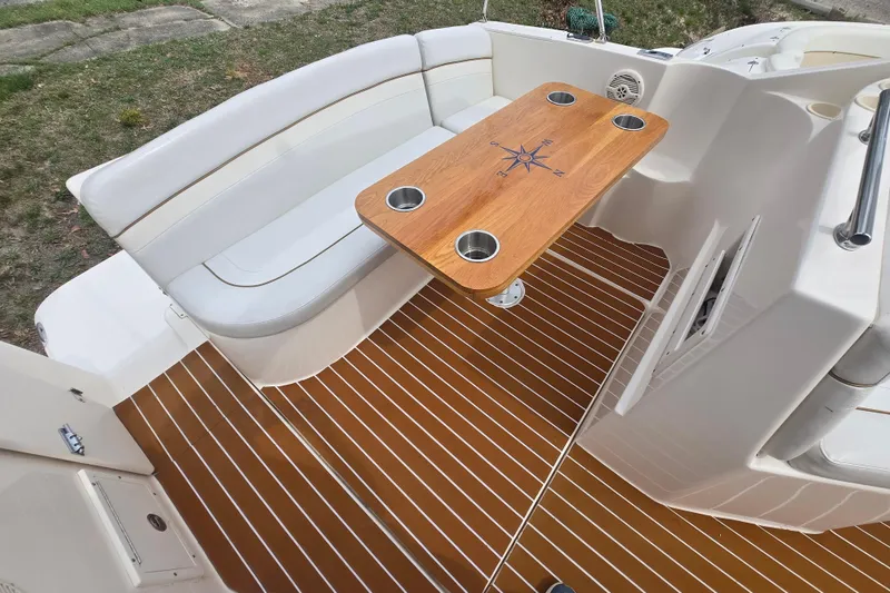 Slide: The Image of 2005 Rinker Fiesta Vee 270 boat interior with wooden table and cushioned seating. - 19